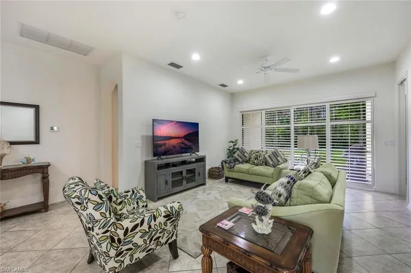 a living room with furniture a flat screen tv and a large window