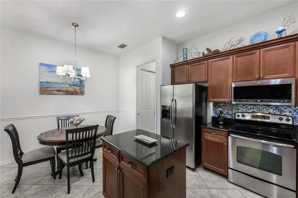 a kitchen with stainless steel appliances granite countertop a stove a refrigerator a kitchen island a dining table and chairs