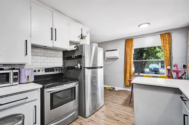 a kitchen with a refrigerator stove and white cabinets with wooden floor