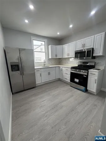 a large kitchen with stainless steel appliances granite countertop a stove a sink a refrigerator a microwave and white cabinets