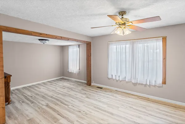 a view of a room with window a ceiling fan and wooden floor