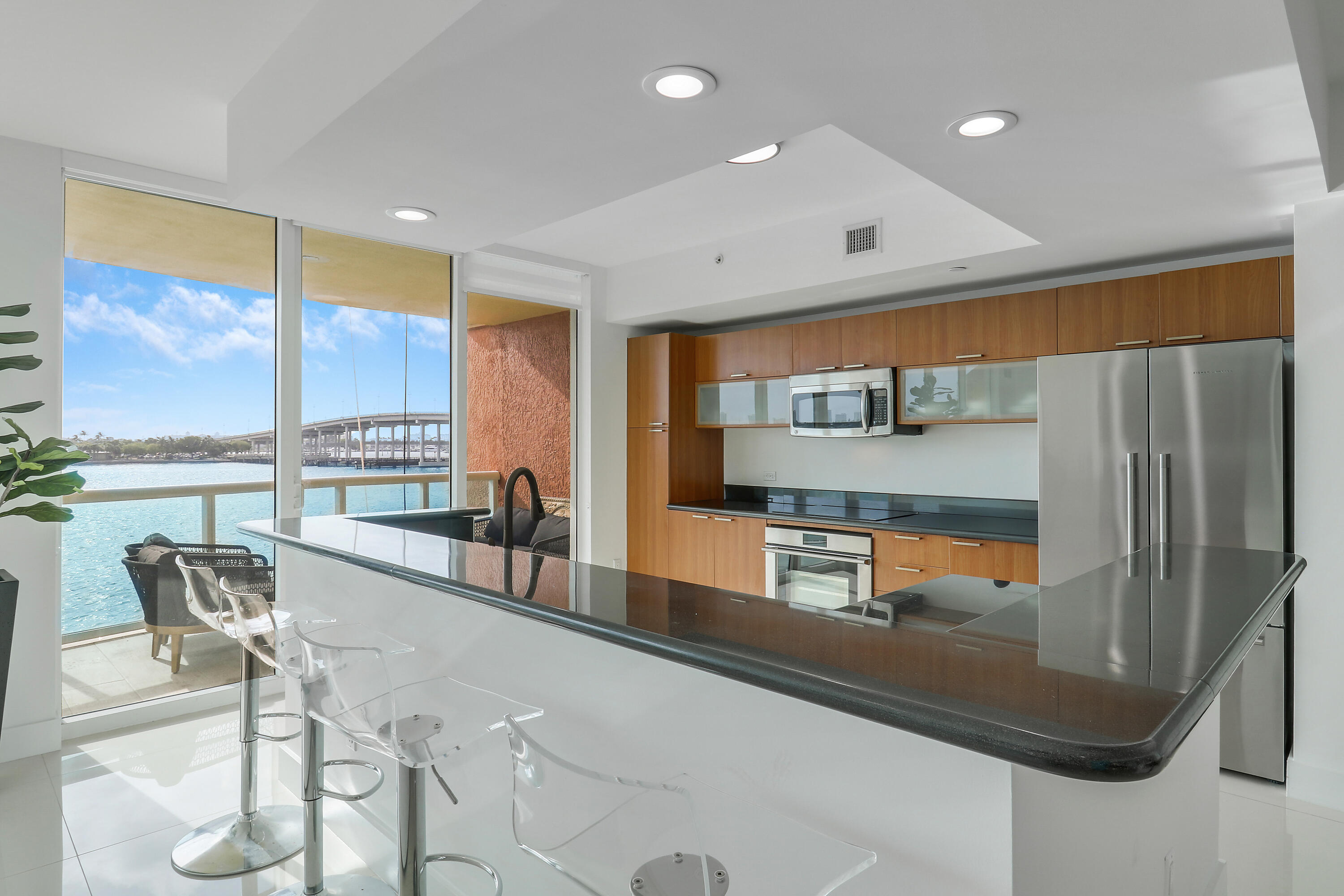 2640 Lake Shore Drive, Unit 307 Riviera Beach, FL 33404 - Photo 9 of 44 a kitchen with stainless steel appliances granite countertop a refrigerator and a view of living room