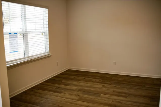 a large kitchen with stainless steel appliances granite countertop a stove a sink a refrigerator and white cabinets with wooden floor