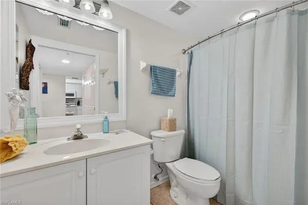 a bathroom with a sink a toilet a mirror and shower curtain