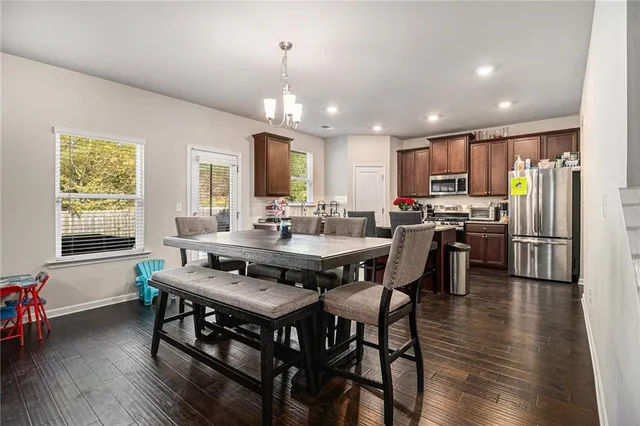 a kitchen with stainless steel appliances a dining table chairs stove refrigerator and cabinets