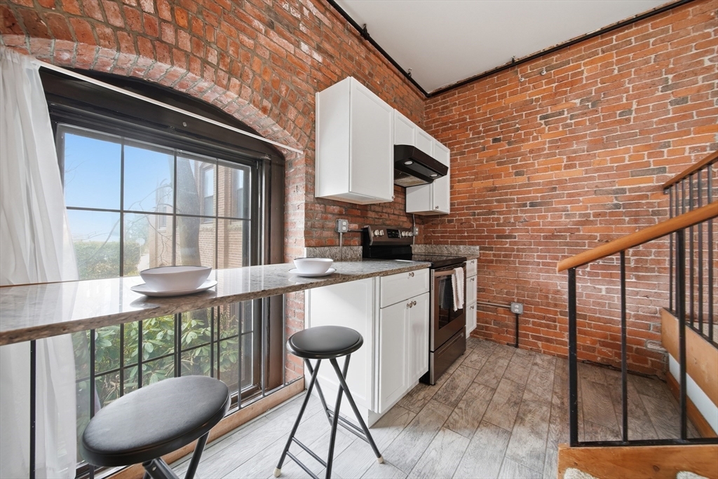 50 Rantoul Street, Unit 204 Beverly, MA 01915 - Photo 23 of 41 a kitchen that has a microwave a table and chairs in it