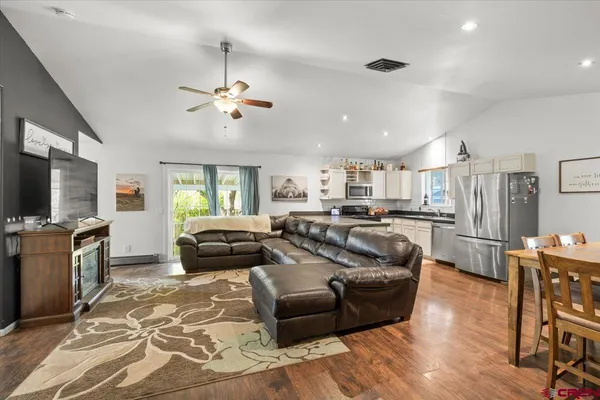 a living room with furniture a flat screen tv and kitchen view