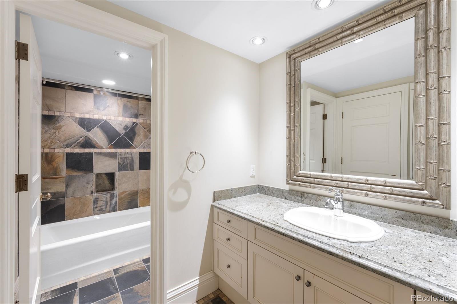 465 Monroe Street Denver, CO 80206 - Photo 39 of 47 a bathroom with a granite countertop sink and a mirror a bathtub