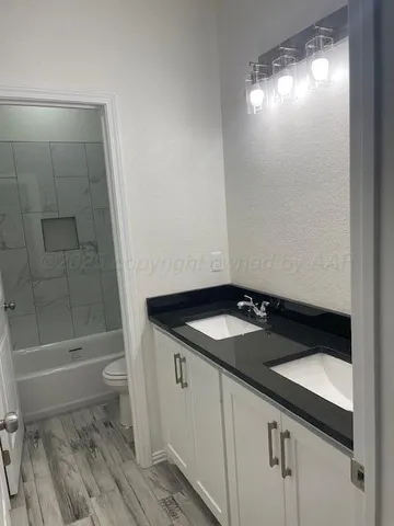 a bathroom with a granite countertop sink a toilet and shower