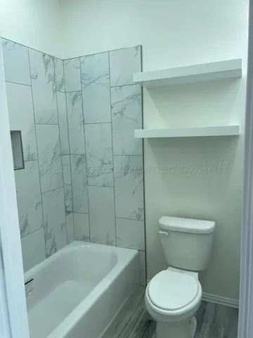a white toilet sitting next to a bathtub