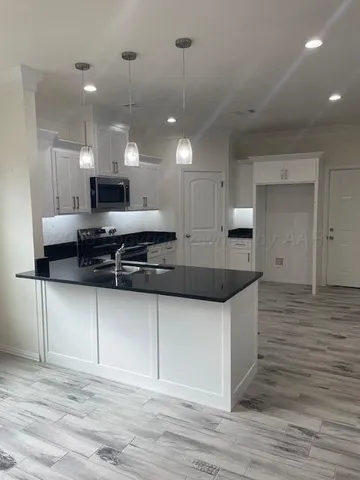 a kitchen with stainless steel appliances granite countertop a sink a stove and a wooden floors