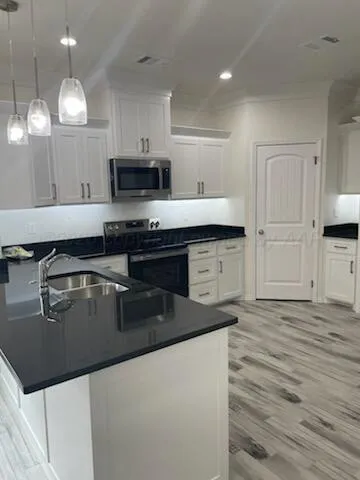 a kitchen with granite countertop a stove a sink and a microwave
