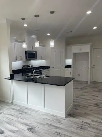 a kitchen with stainless steel appliances granite countertop a sink a stove and a wooden floors