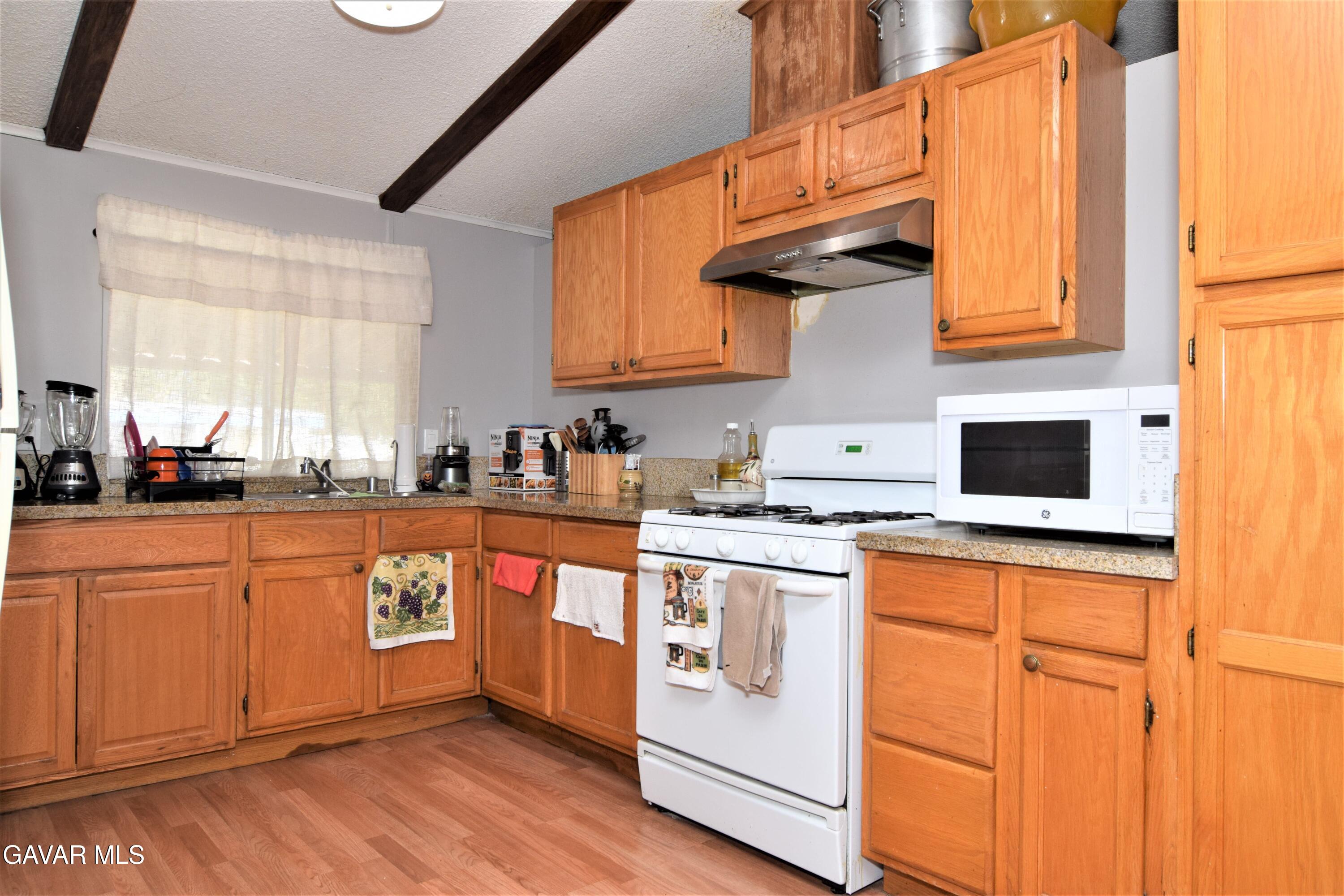 45446 7th Street East Lancaster, CA 93535 - Photo 11 of 21 a kitchen with stainless steel appliances granite countertop a stove a sink and white cabinets