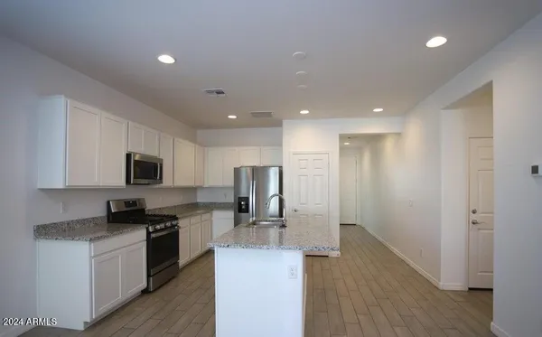 a kitchen with stainless steel appliances granite countertop a refrigerator a stove a sink a washer and dryer