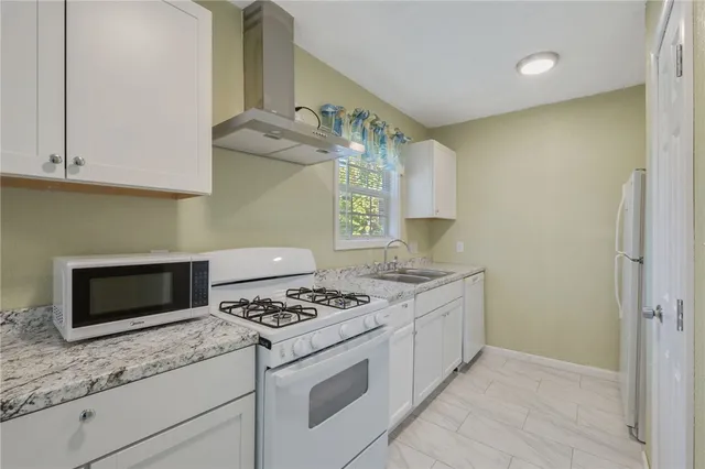 a kitchen with granite countertop stainless steel appliances a stove and a microwave