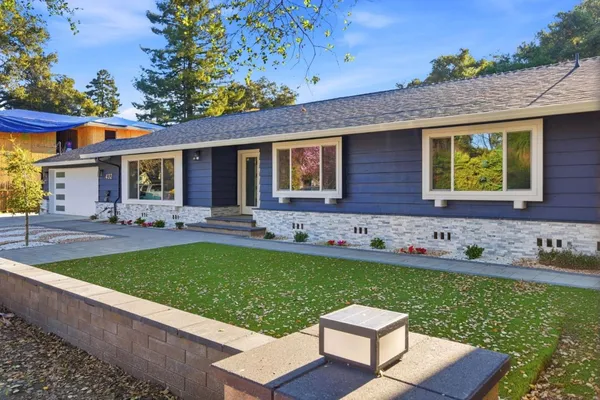 a front view of a house with garden and trees
