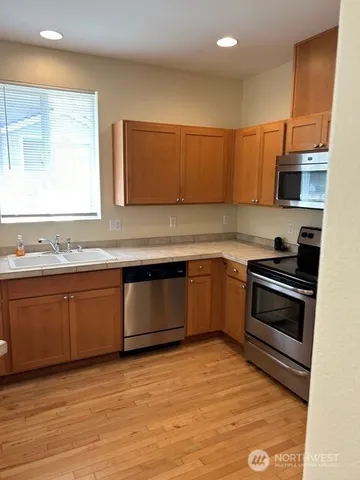 a kitchen with granite countertop a sink cabinets and stainless steel appliances