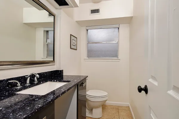 a bathroom with a granite countertop sink toilet and mirror