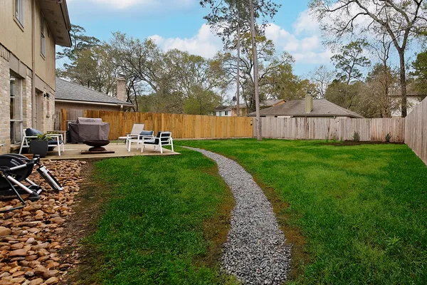 a view of a backyard with table and chairs a fire pit and wooden fence
