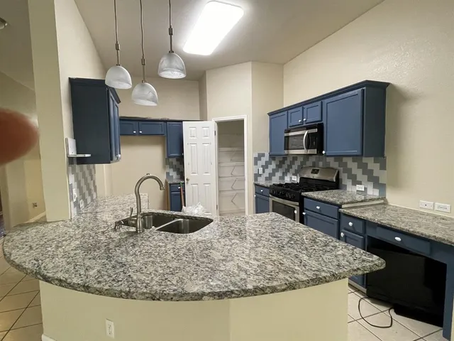 a kitchen with stainless steel appliances granite countertop a sink a stove refrigerator and microwave