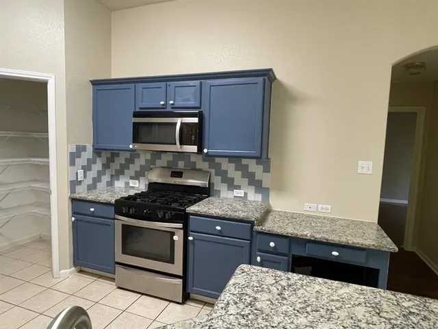 a kitchen with stainless steel appliances kitchen island granite countertop a stove a sink and a microwave