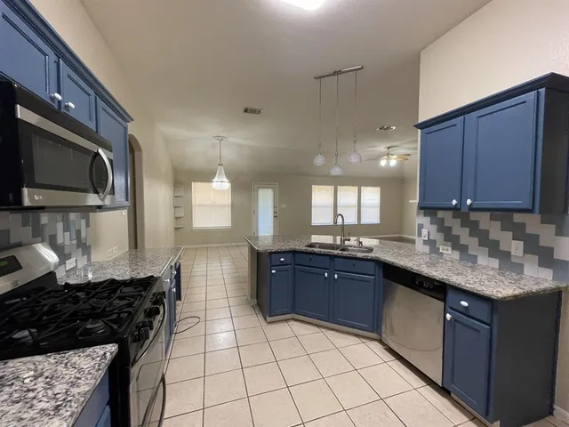 a kitchen with stainless steel appliances granite countertop a stove a sink and a microwave