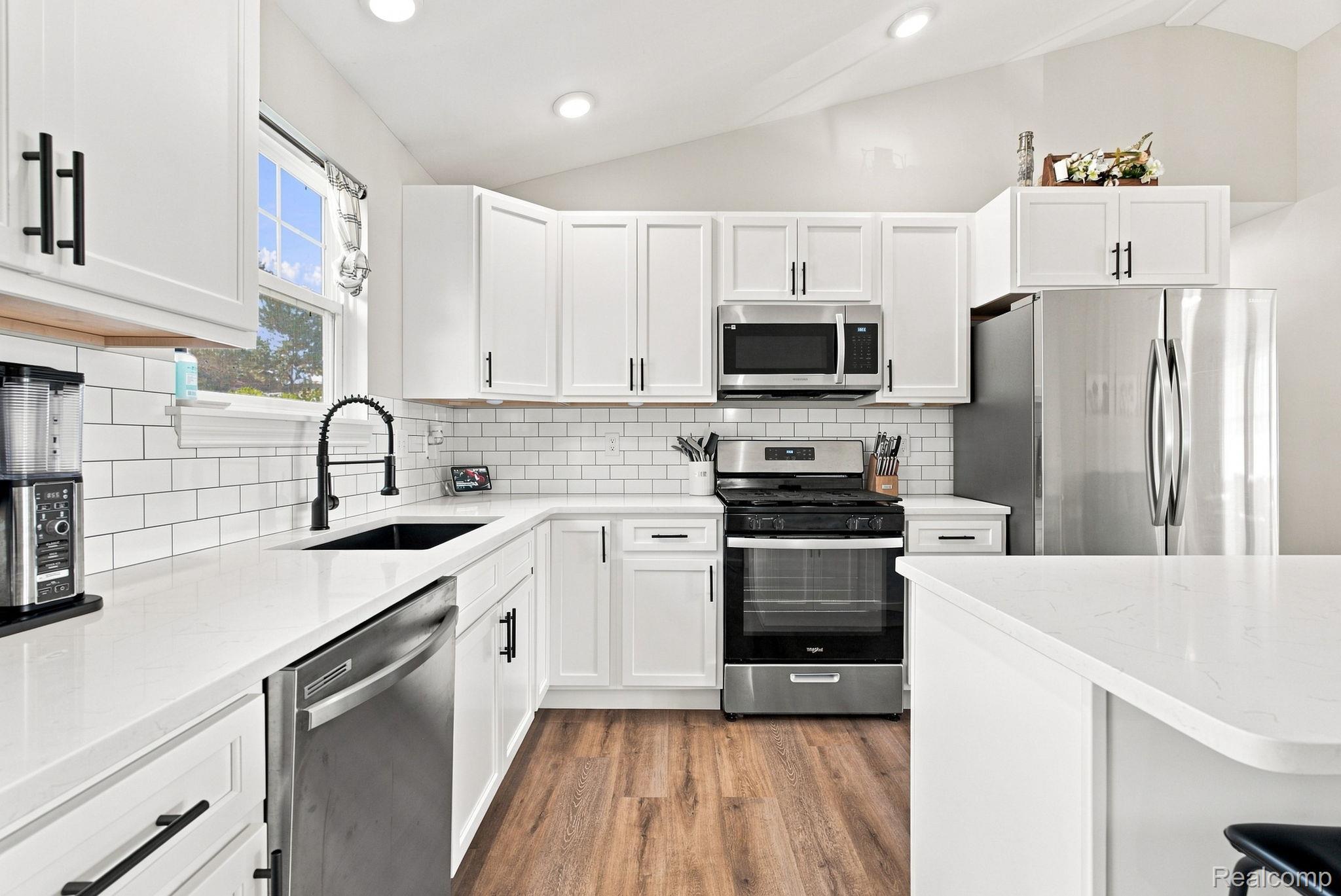 629 Range Road Smiths Creek, MI 48074 - Photo 17 of 36 White cabinetry with matte black hardware, stainless steel appliances, white subway tile backsplash, light-toned countertops, and wood-finish flooring