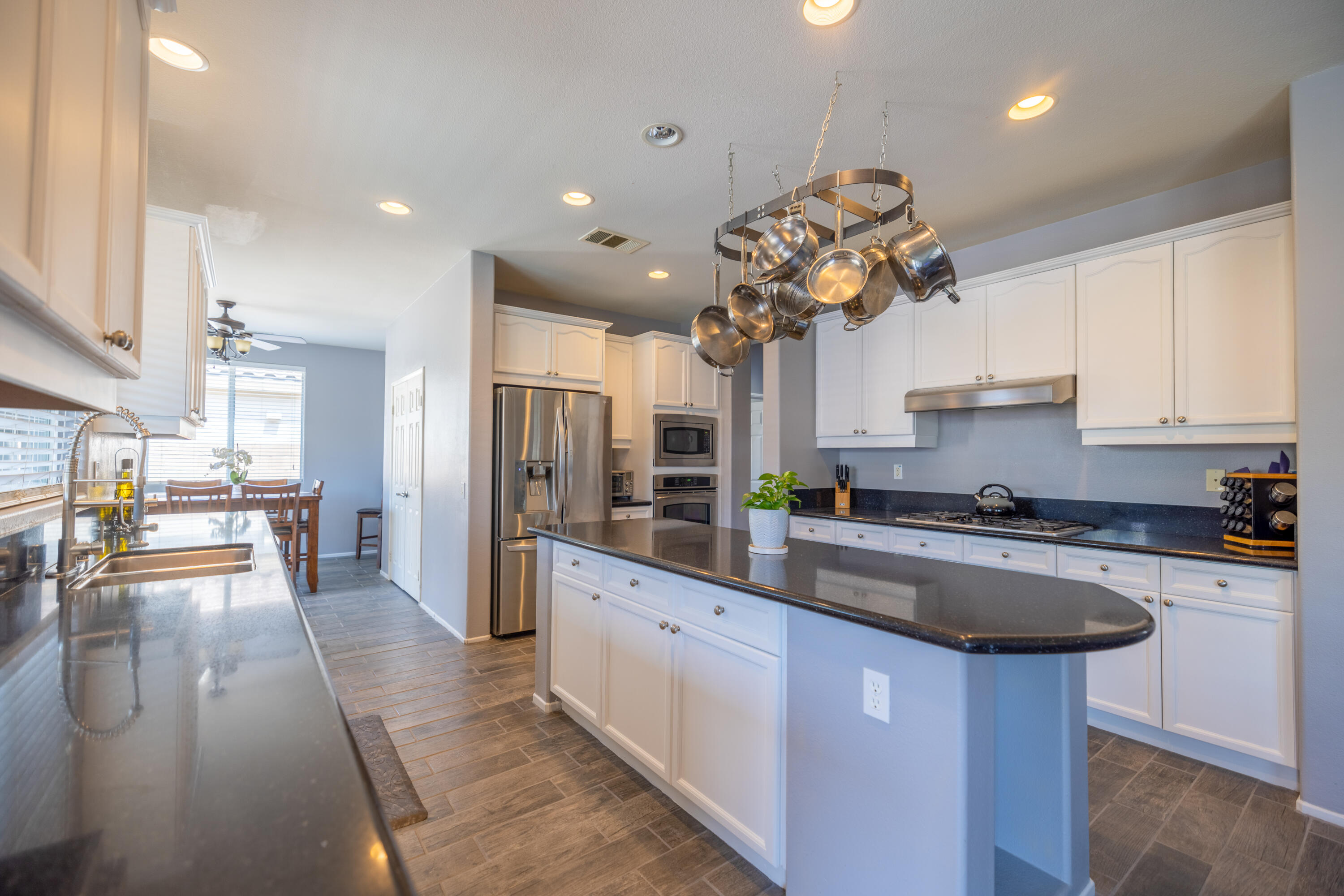 83332 Lone Star Road Indio, CA 92203 - Photo 7 of 33 a kitchen with stainless steel appliances granite countertop a sink dishwasher a microwave oven and a dining table with wooden floor