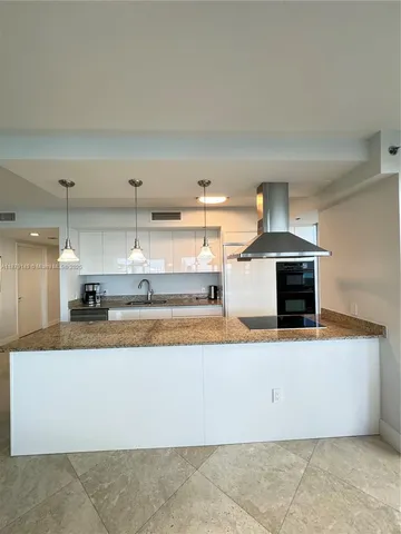 a large kitchen with stainless steel appliances a stove and a sink with granite countertops