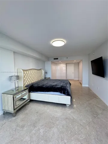 a spacious bedroom with a bed and a flat screen tv