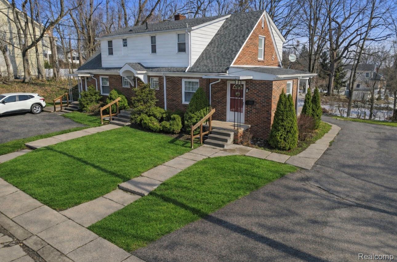 224 Chandler Street Romeo, MI 48065 - Photo 2 of 28 Traditional-style home with brick siding, roof with shingles, a front yard, and a chimney