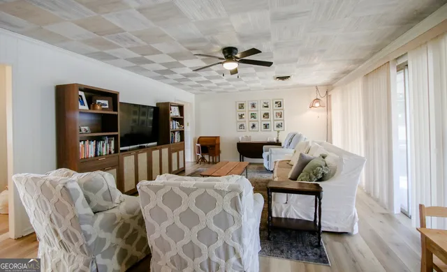 a living room with furniture a flat screen tv and a bookshelf