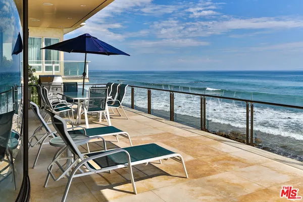 a roof deck with table and chairs under an umbrella