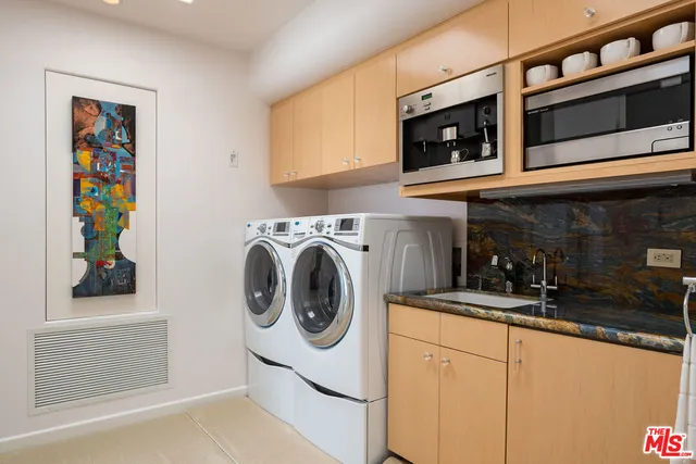 a utility room with stainless steel appliances white cabinets and a sink