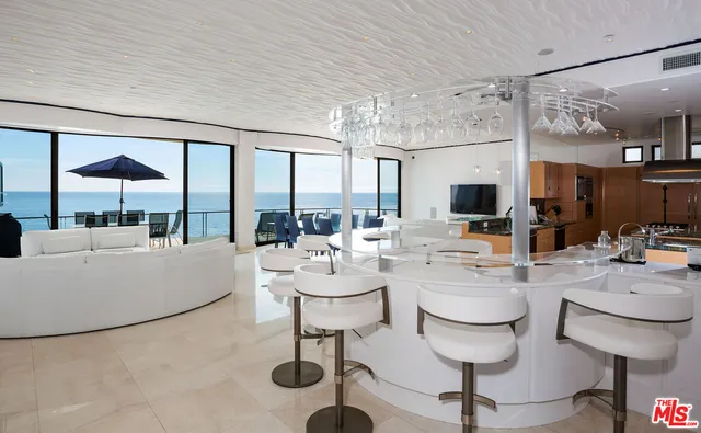 a living room with couches a coffee table and kitchen view with wooden floor