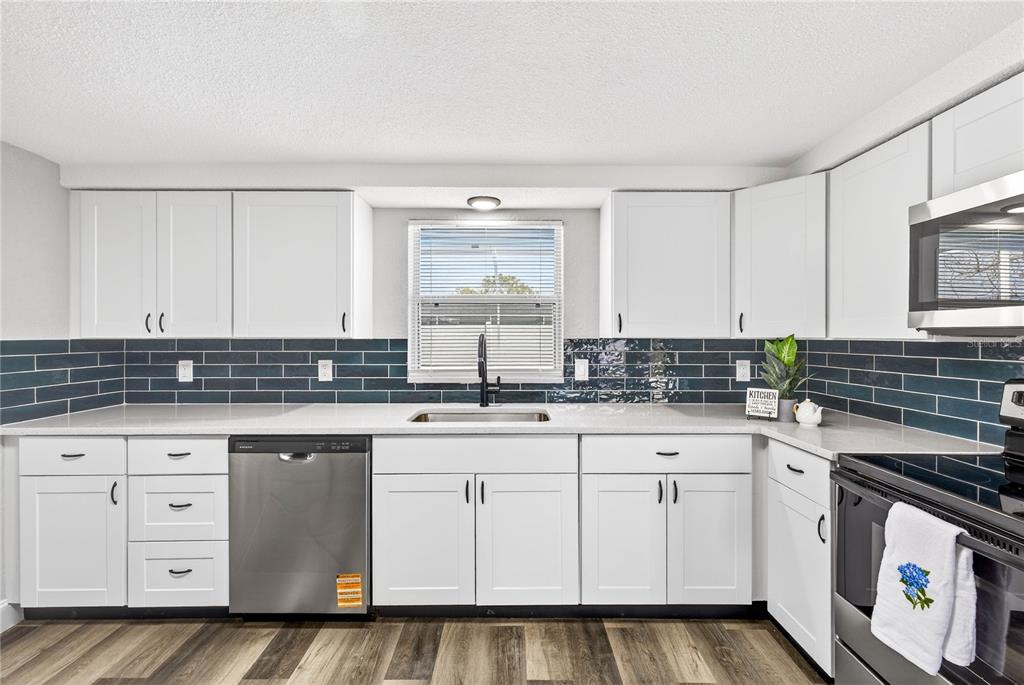 11214 Kapok Avenue Port Richey, FL 34668 - Photo 12 of 25 a kitchen with white cabinets sink and stove