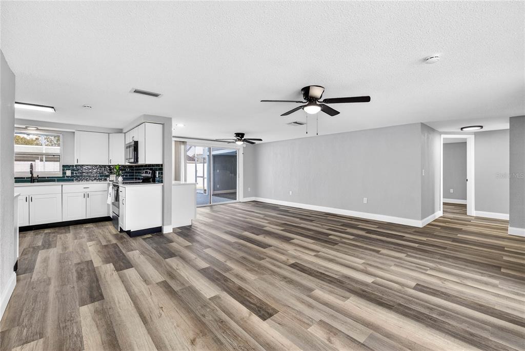 11214 Kapok Avenue Port Richey, FL 34668 - Photo 7 of 25 a view of a kitchen with wooden floor and a ceiling fan