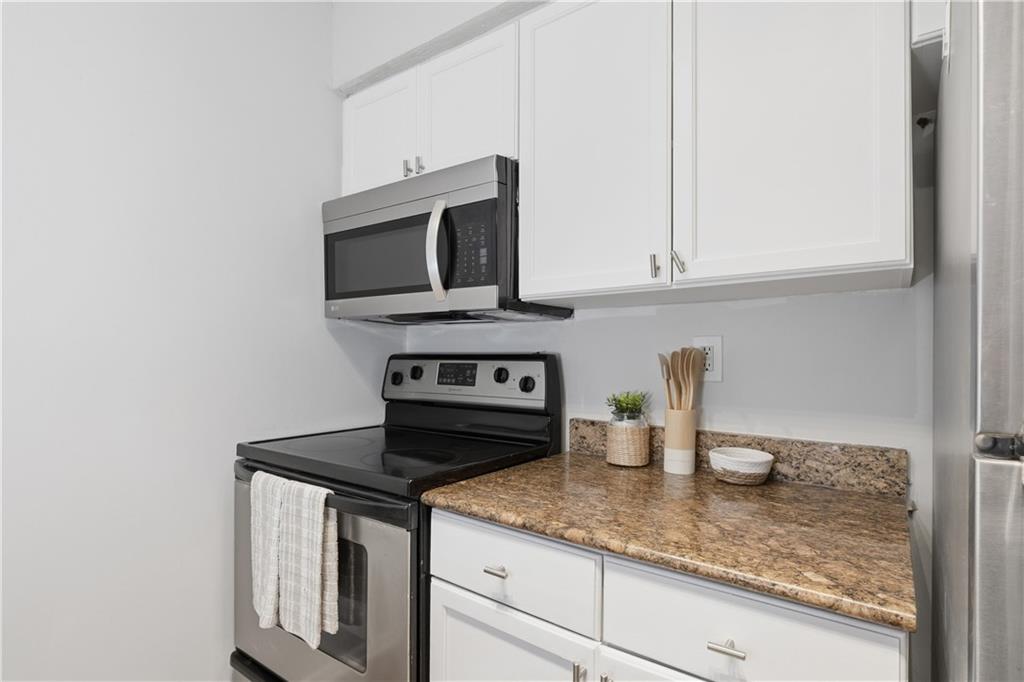 1150 Collier Road Northwest, Unit 6H Atlanta, GA 30318 - Photo 14 of 29 a kitchen with white cabinets and appliances