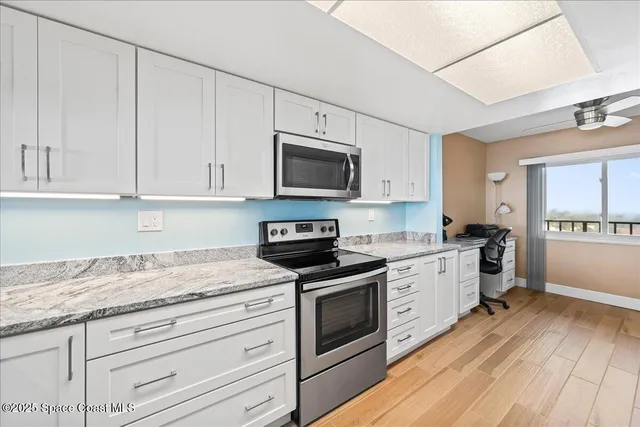 a kitchen with granite countertop white cabinets and white appliances