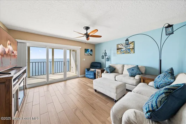 a living room with furniture two large windows and a flat screen tv