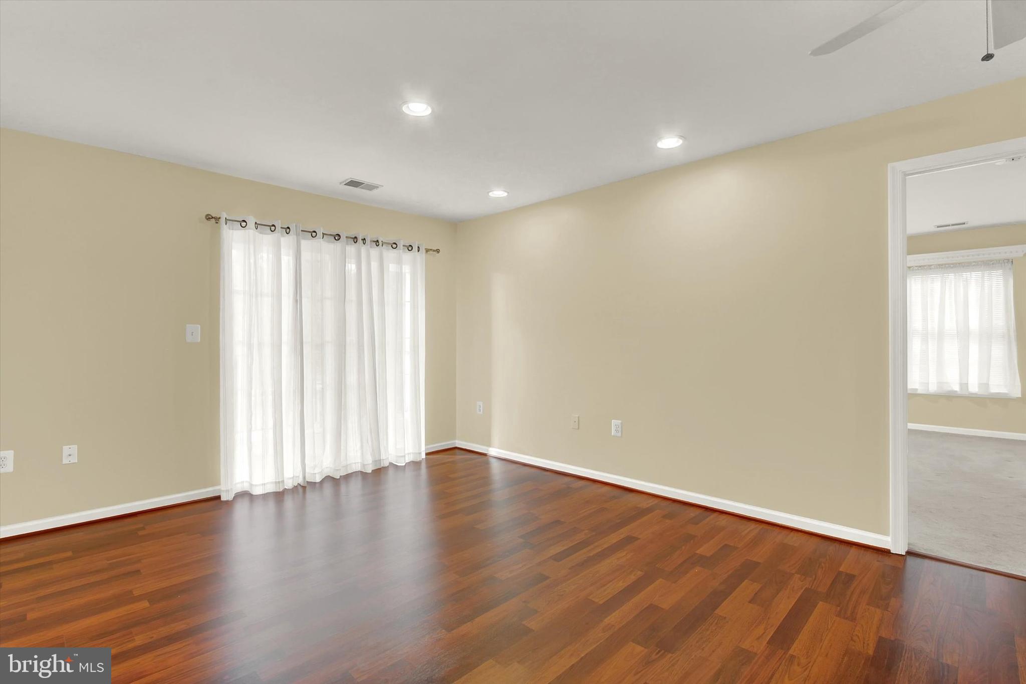 6500 Ridenour Way East, Unit 3C Sykesville, MD 21784 - Photo 5 of 22 an empty room with wooden floor and windows with curtains