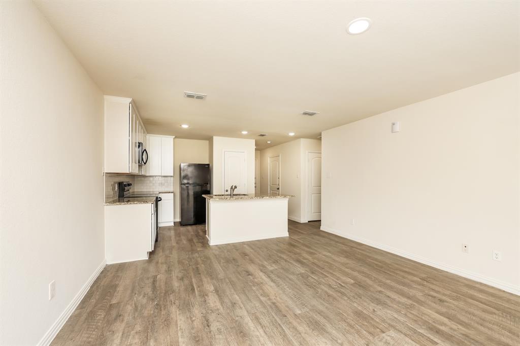 2712 William Street Mabank, TX 75147 - Photo 6 of 20 a view of a kitchen with kitchen island a sink wooden floor and a refrigerator