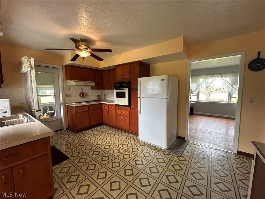 2408 Brown Road Ashtabula, OH 44004 - Photo 10 of 27 Kitchen with ceiling fan, sink, white appliances, backsplash, and light wood-type flooring