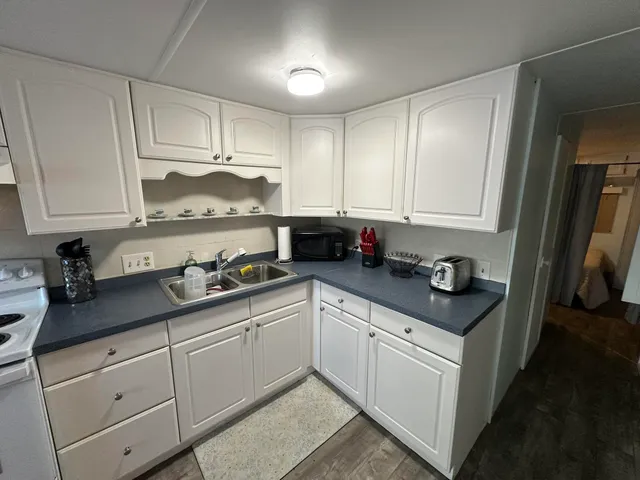 a kitchen with granite countertop white cabinets and white appliances