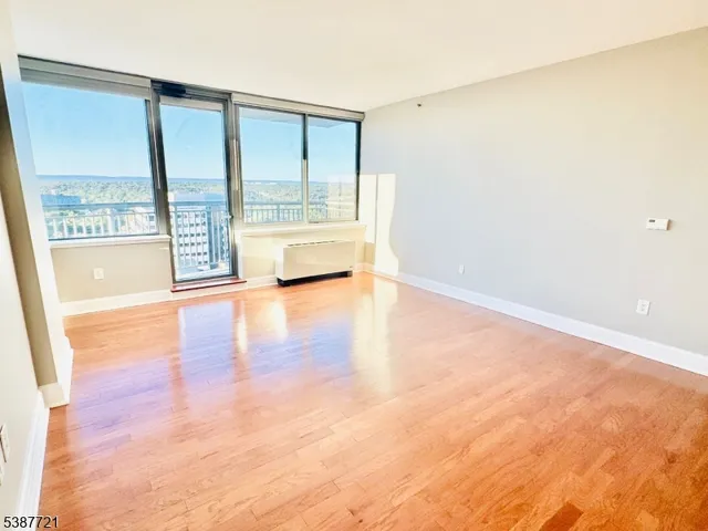 a view of an empty room with wooden floor and a shower