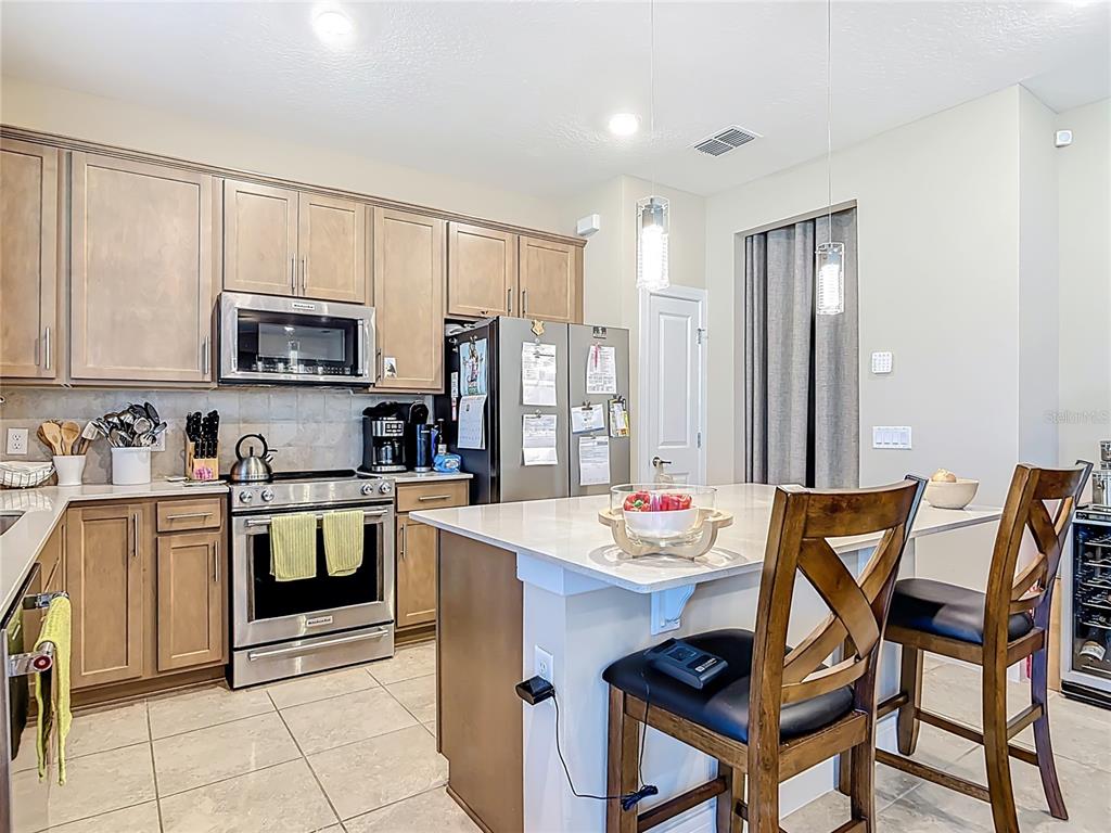 2248 Canopy Terrace Boulevard DeLand, FL 32724 - Photo 8 of 49 a kitchen with stainless steel appliances kitchen island granite countertop a table chairs and a refrigerator