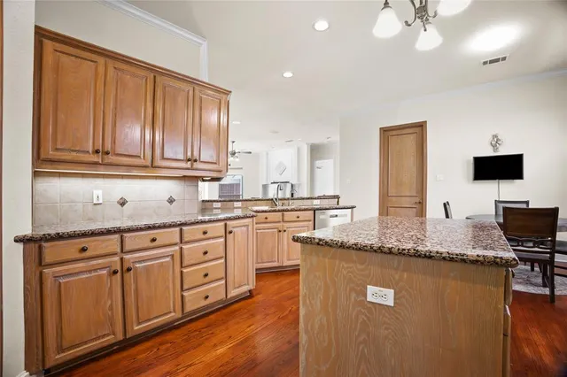 a kitchen with granite countertop a sink cabinets and wooden floor