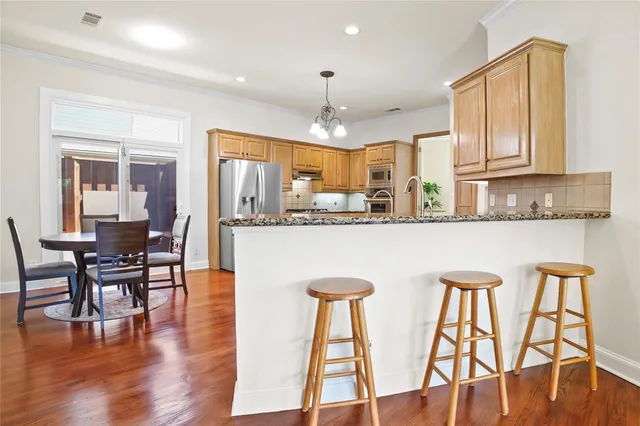 a kitchen with stainless steel appliances granite countertop a kitchen island hardwood floor and a refrigerator