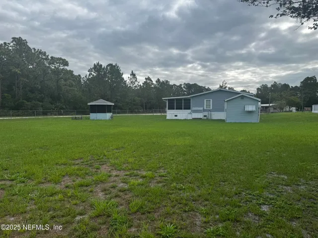 a view of a house with a big yard and a large tree